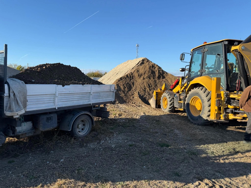 Buldoexcavator CAT încarcă remorcă cu pământ Prahova